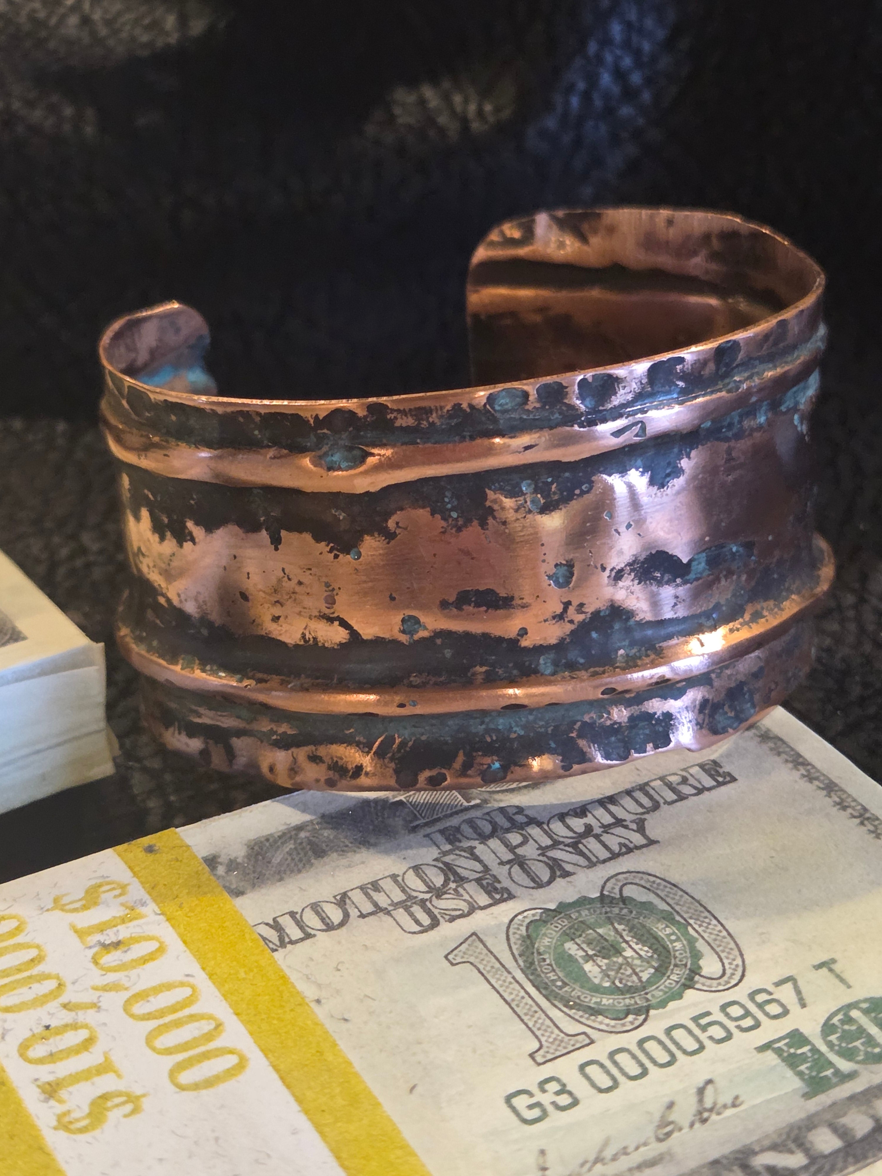 Copper bracelet next to a $100.00 bill