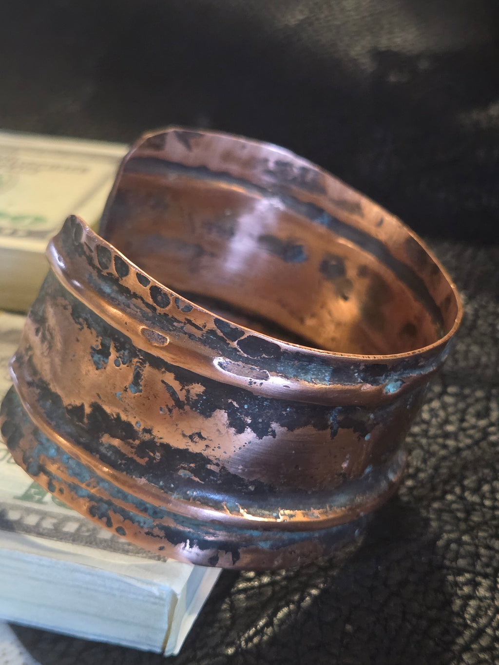 Copper bracelet with black patina on a textured surface