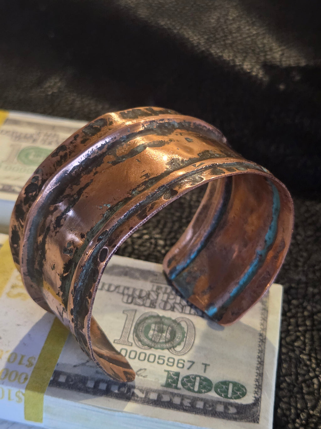 Copper pipe fitting on top of a one hundred dollar bill